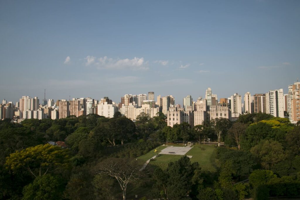 Bairro Vila Mariana, São Paulo. Céu azul, com prédios ao fundo e parque arborizado.