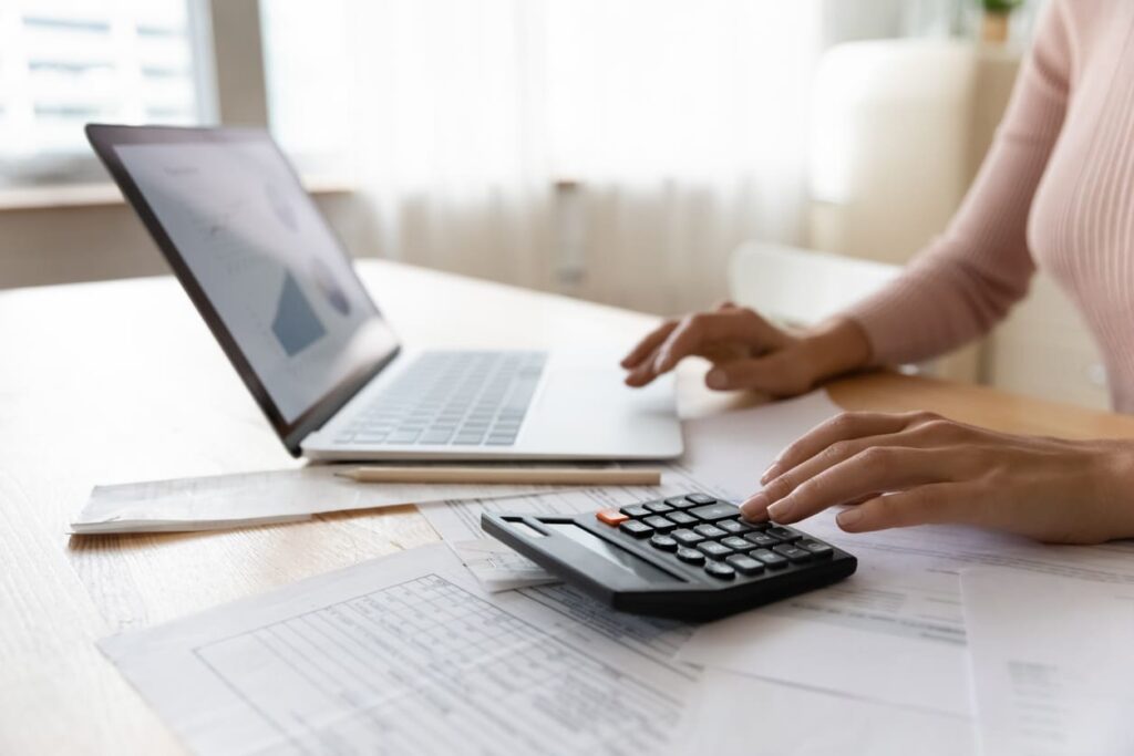 Um pessoa usando um notebook e calculadora em uma mesa.