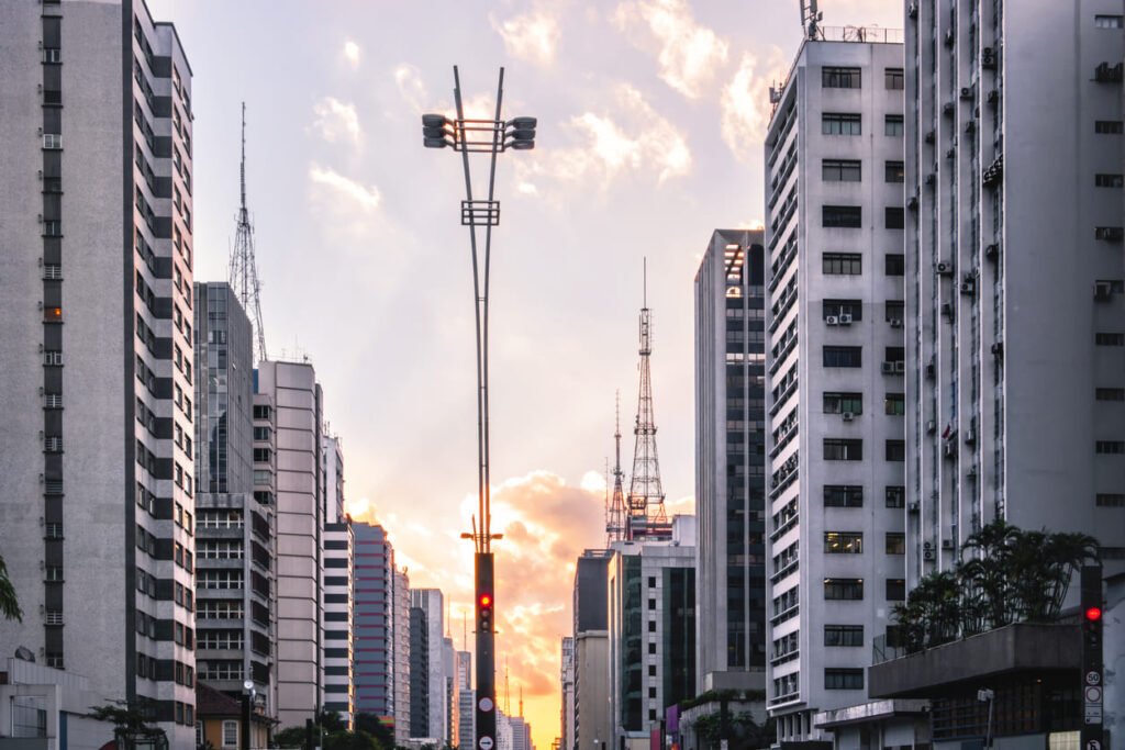 Foto tirada do horizonte com prédios ao lado e pôr do sol ao fundo na avenida paulista, São Paulo.