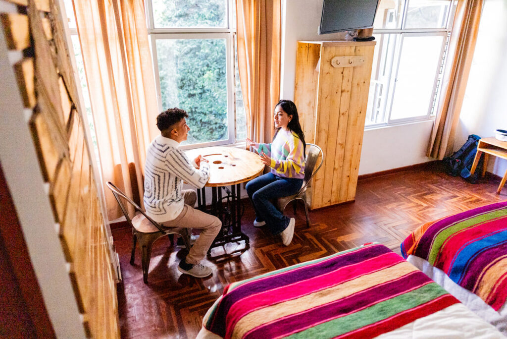 Casal jovem em um apartamento durante o dia conversando e sentados à mesa.
